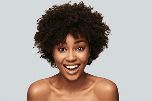 image of woman with afro hair smiling and skin glowing